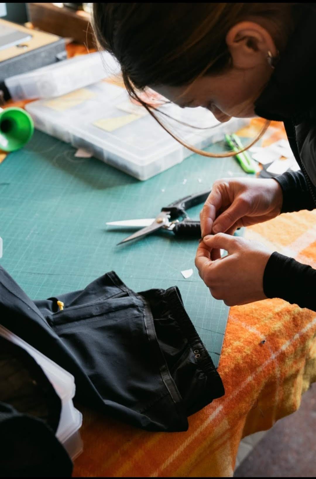 A closeup image of Abi (owner) fixing the leg of a snow bib with a patch.