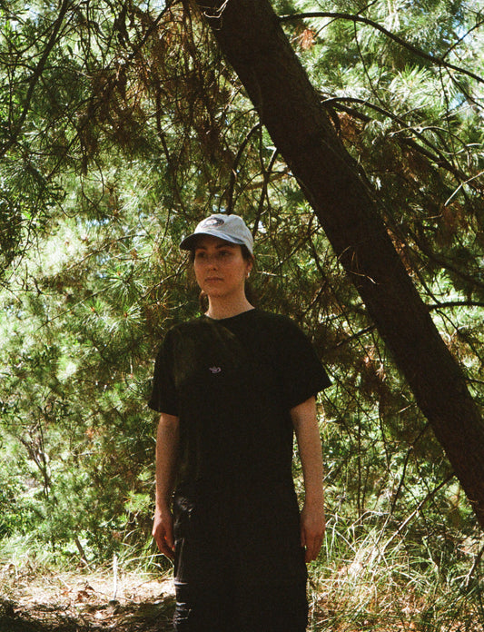 A woman wearing a black tee standing in some trees