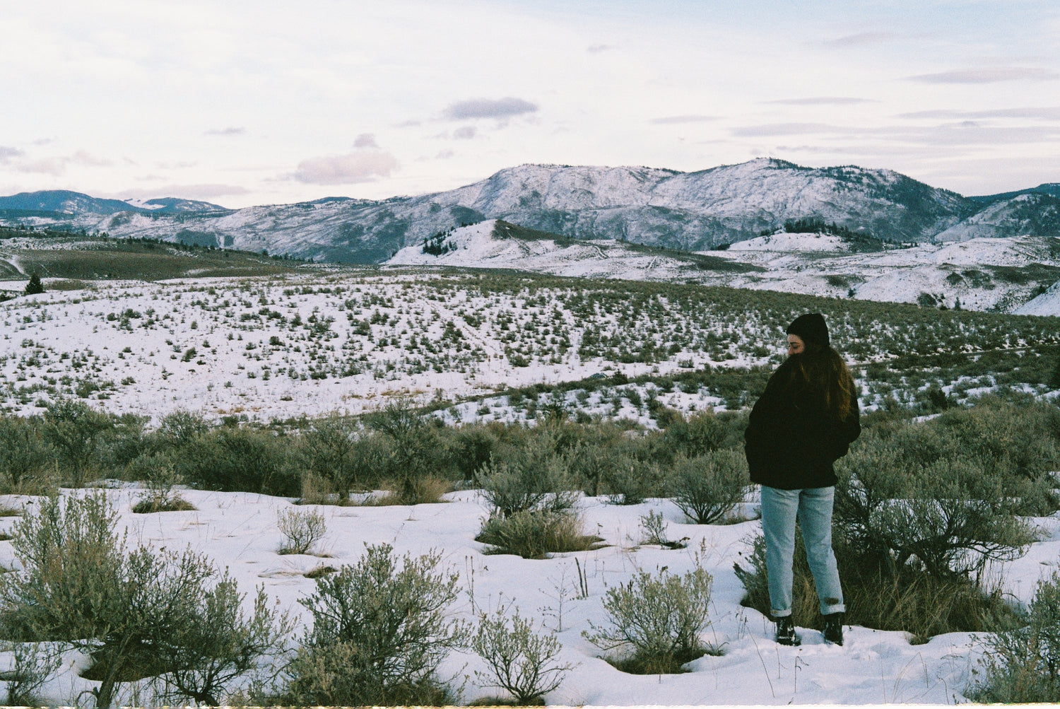 Founder, Abi, standing in a snowy field with her back to the camera in rural canada