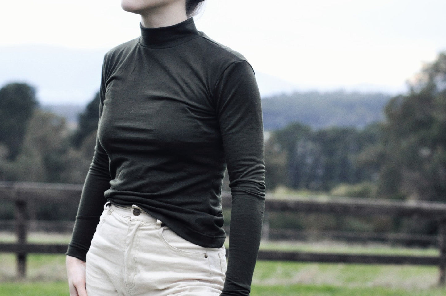 a close up of a woman wearing an olive tight long sleeve shirt
