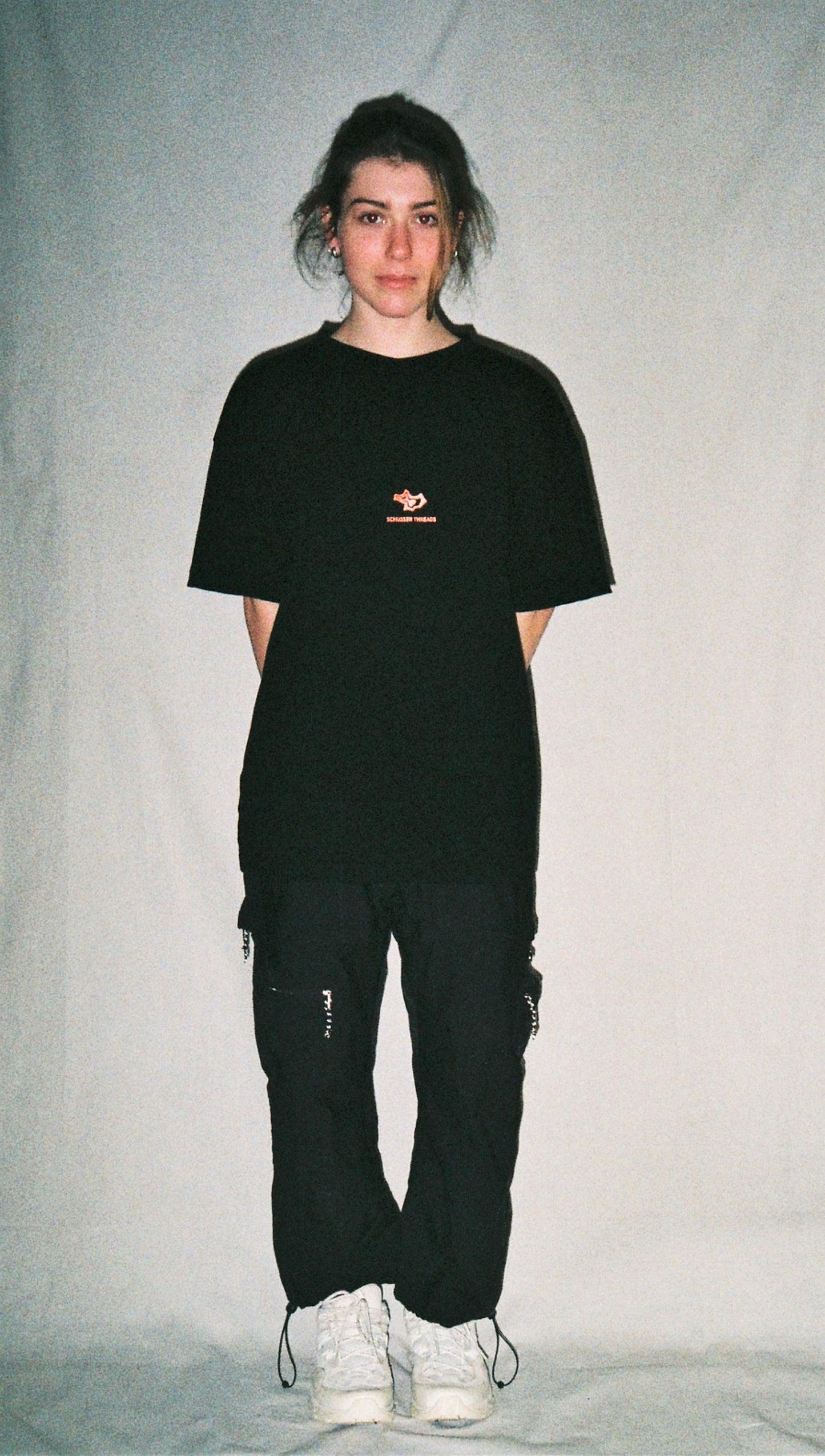 A girl wearing a black tee shirt with a red logo in front of a white background.