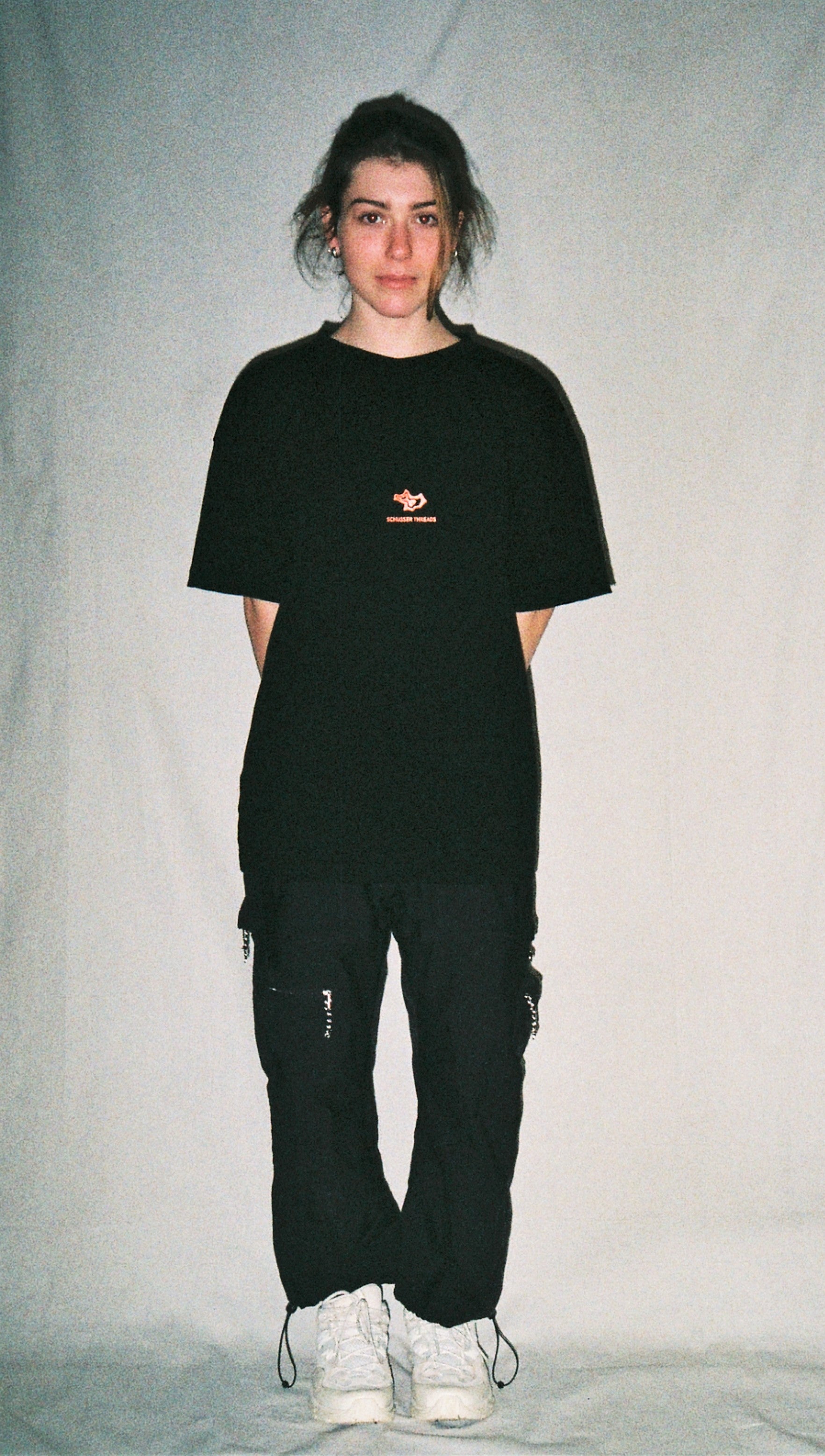 A girl wearing a black tee shirt with a red logo in front of a white background.