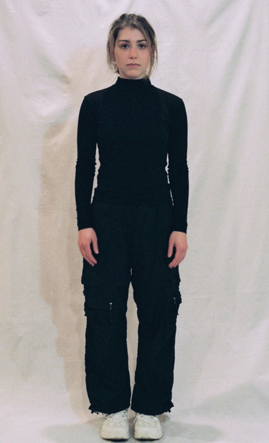 A front photo of a girl standing in front of a white background wearing a black ong sleeve shirt