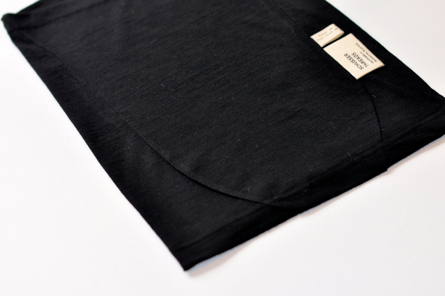 A close up image of a black neck tube with seam detailing and a natural coloured tag