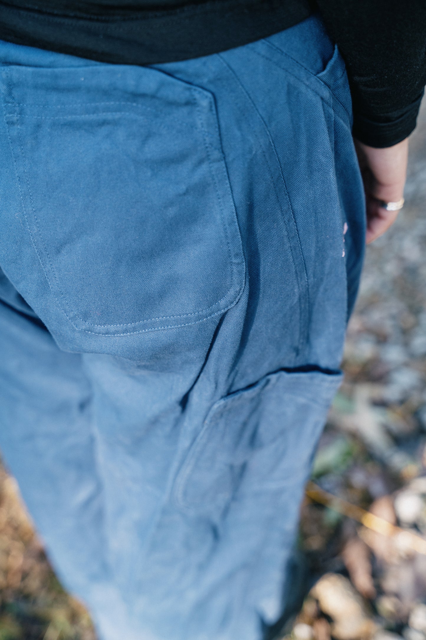 A detailed back photo of the back pocket on a blue pair of pants