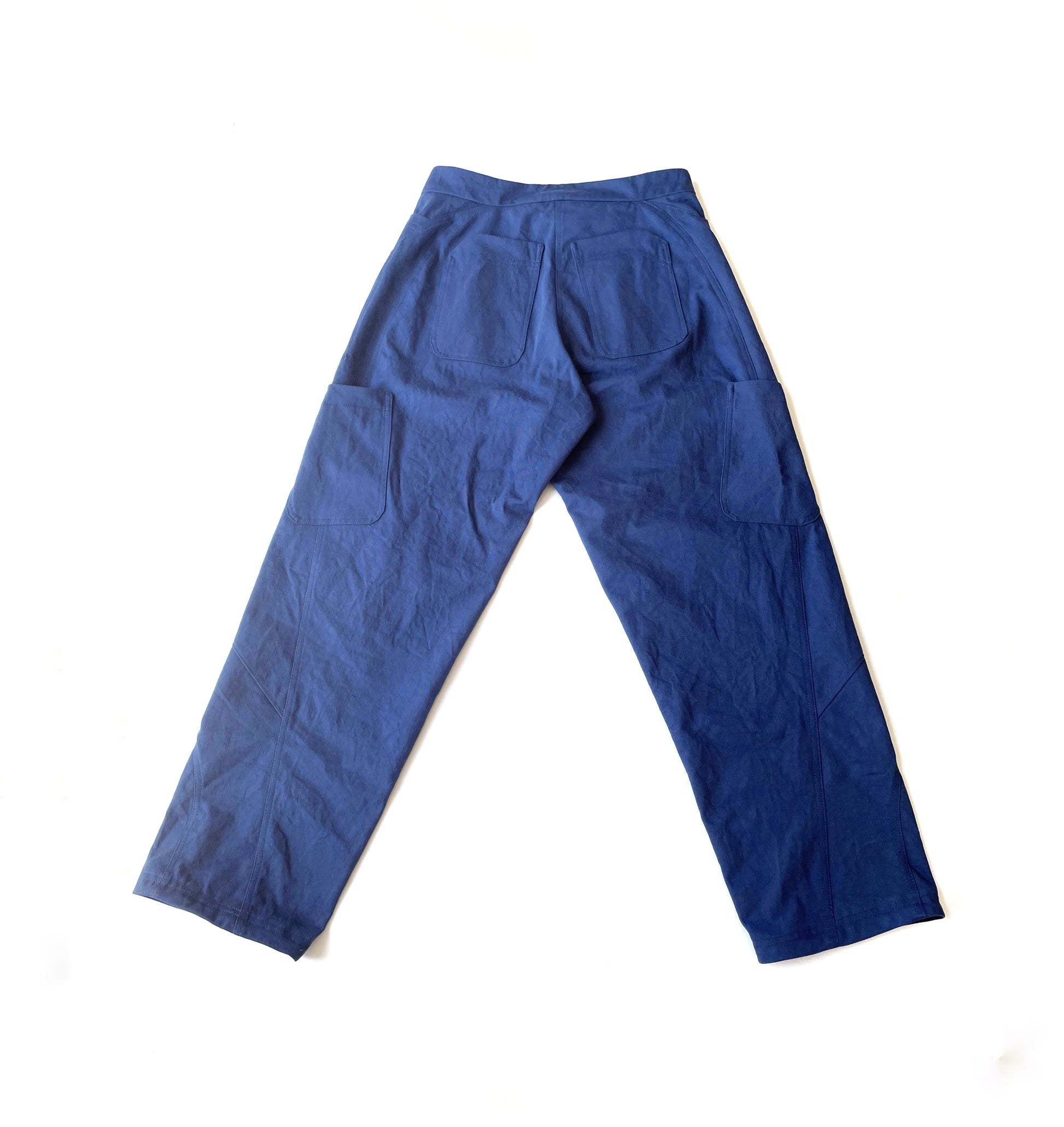 A back flat lay photo of a blue pair of pants with back and side pockets with a purple logo 