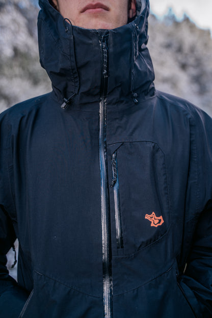 An image of the top of a jacket with a peach coloured logo on a chest pocket.