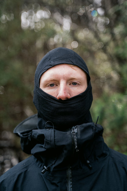 A man facing the camera wearing a black balaclava