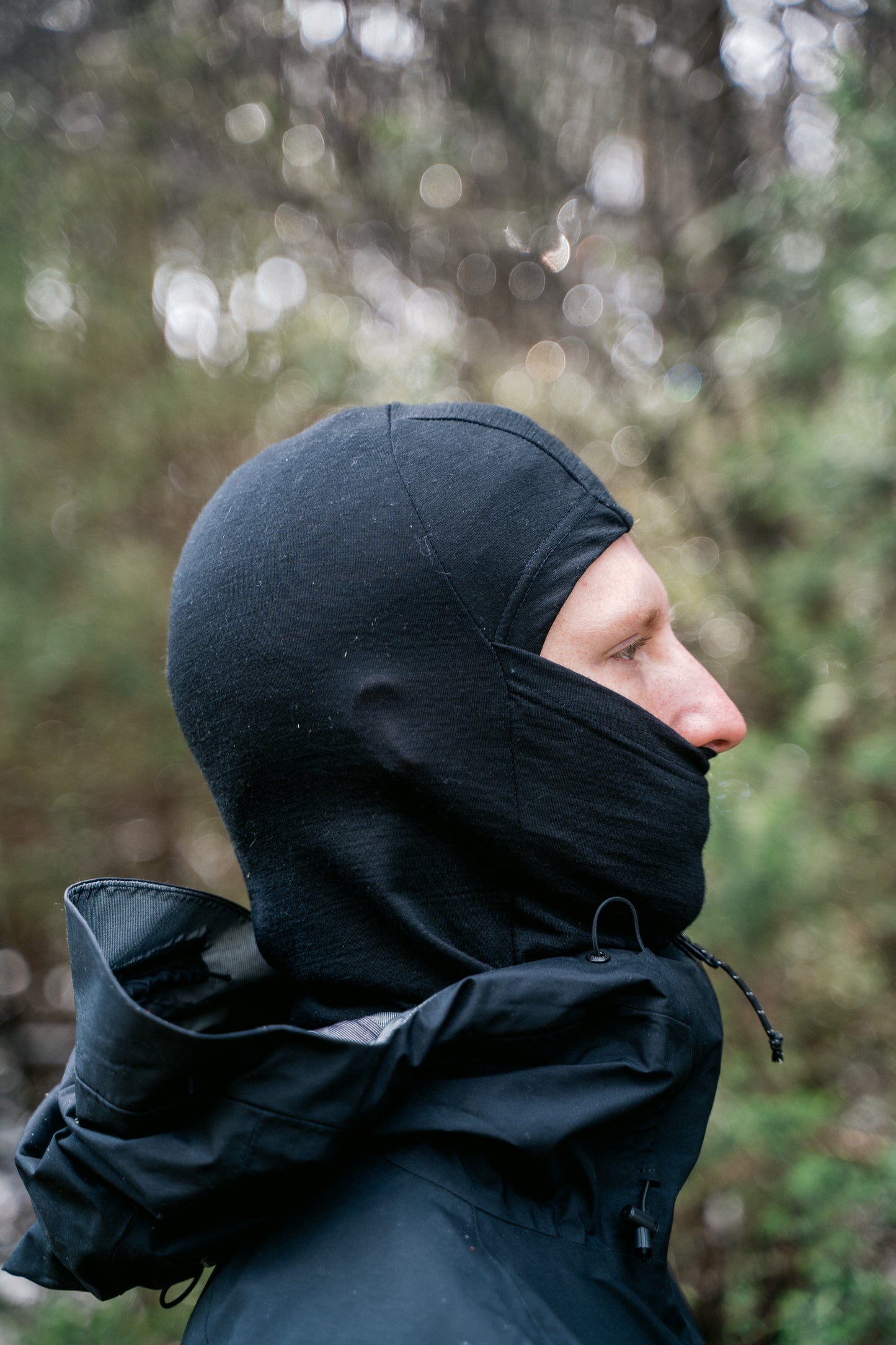 A man wearing a black balaclava facing side on to the camera.