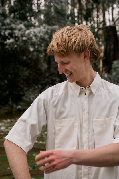 A man in a white shirt looking at the sleeve and adjusting the length.