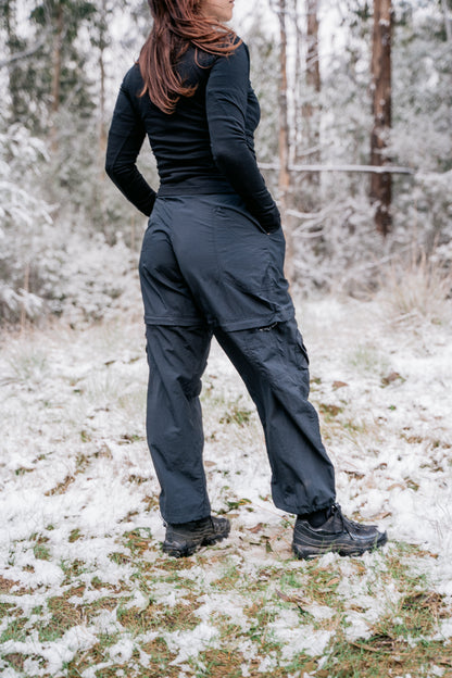 A woman standing in the grass with a light dusting of snow around her