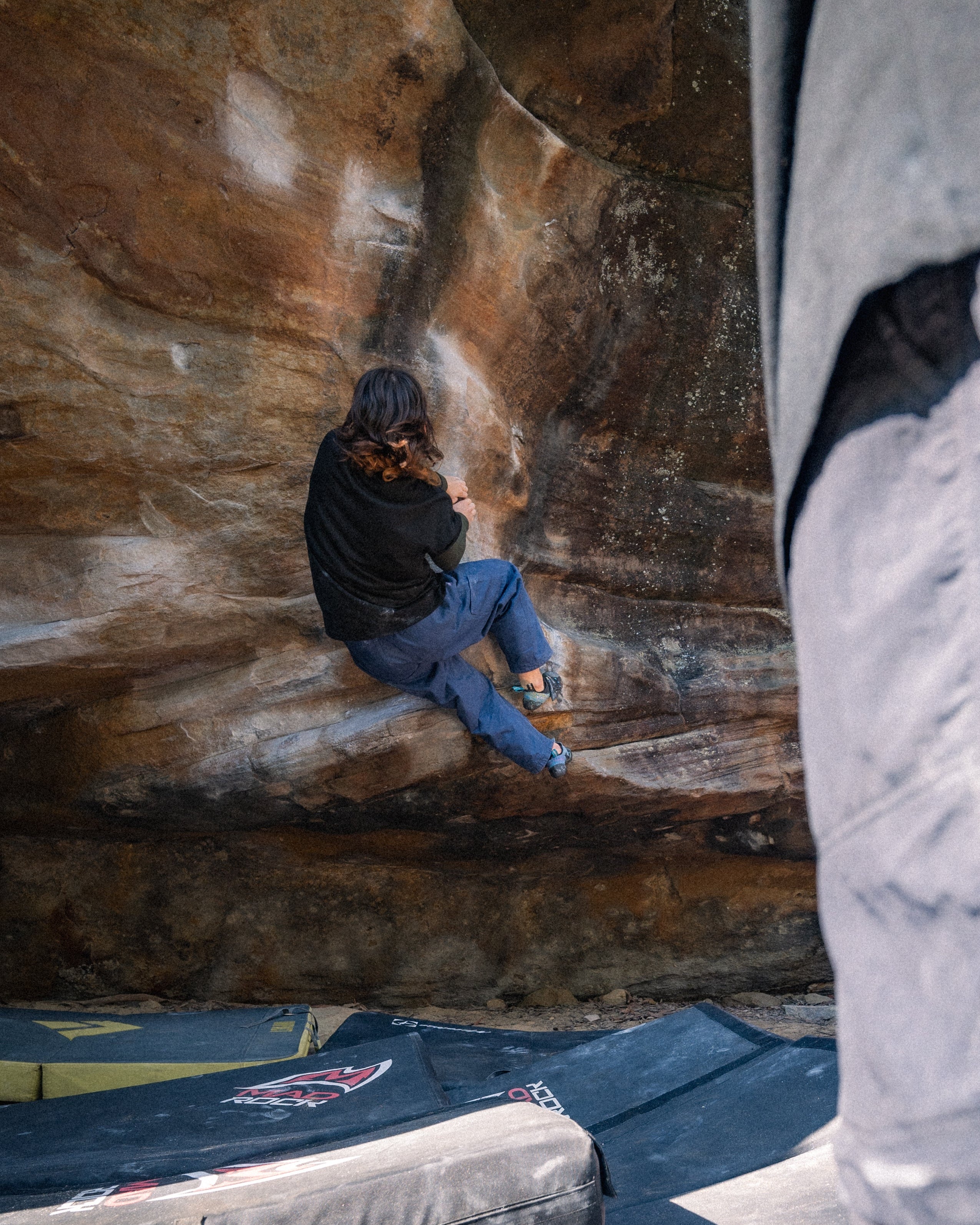 a girl bouldering on a red rock wall