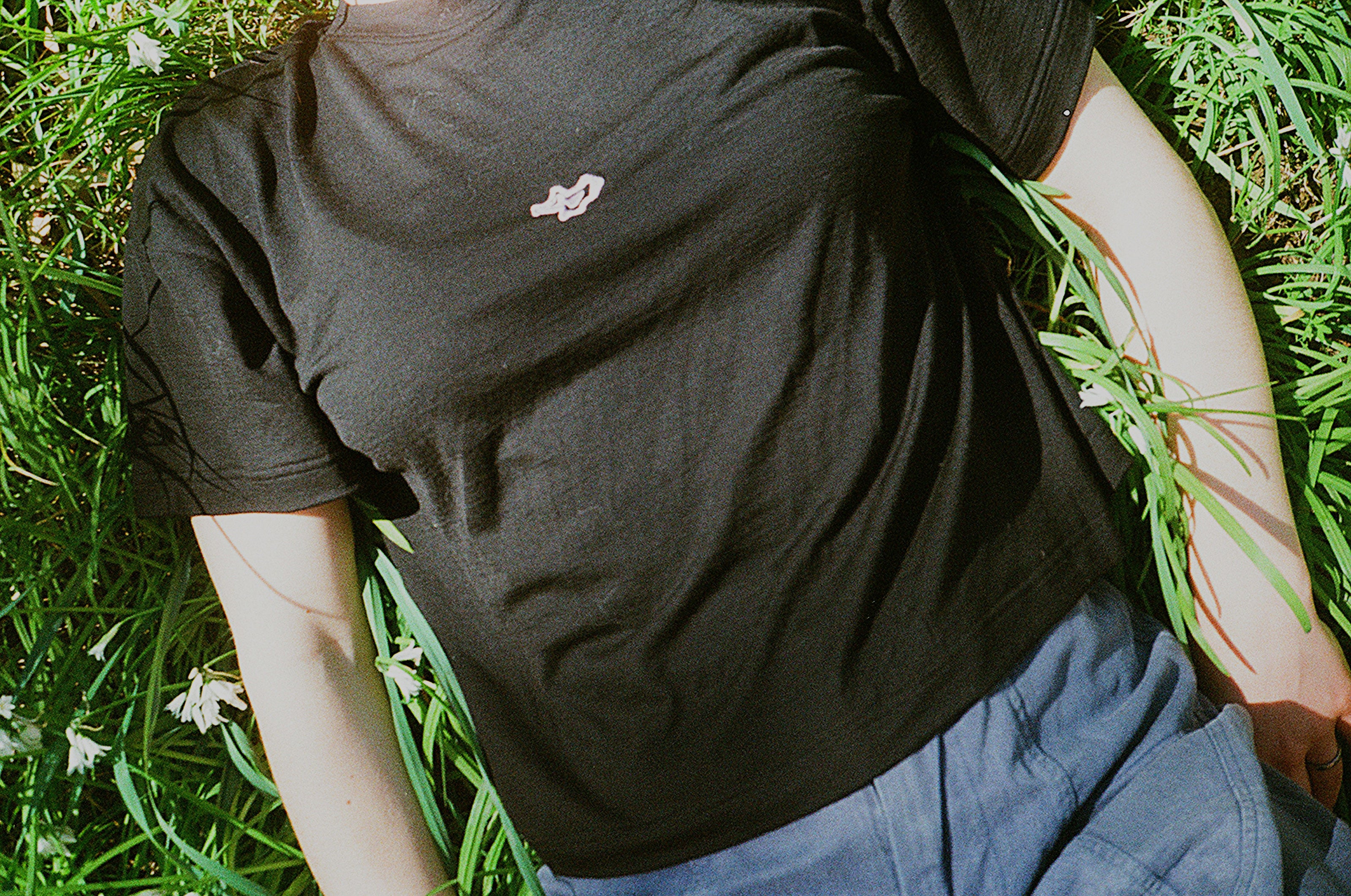 A person lying on the grass in a black shirt