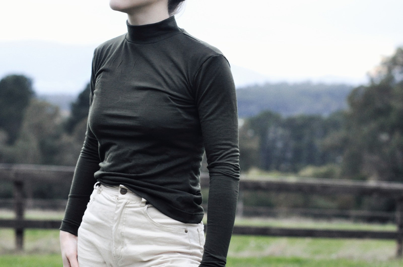 a close up of a woman wearing an olive tight long sleeve shirt