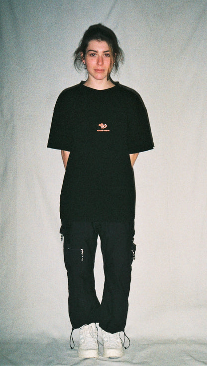 A girl wearing a black tee shirt with a red logo in front of a white background. 