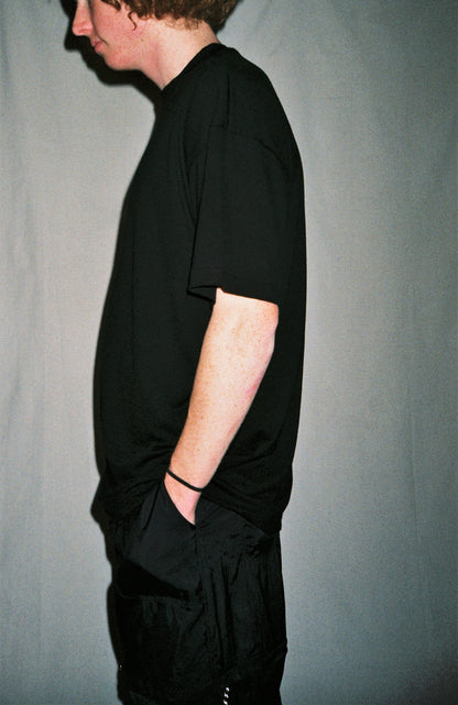 A man standing in front of a white background wearing a black shirt