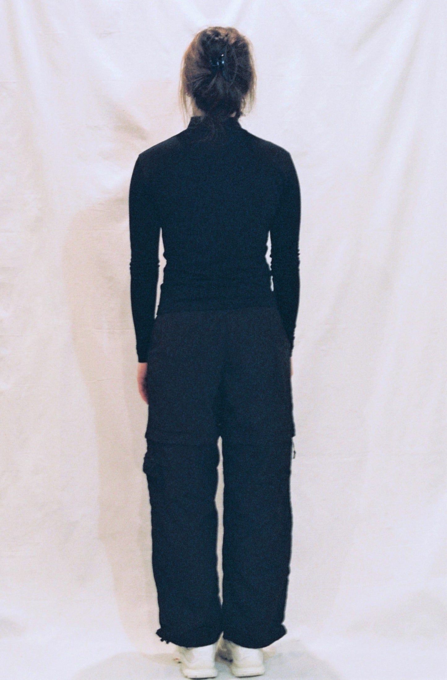 An image of a girl with her back to the camera wearing a black long sleeve shirt. 