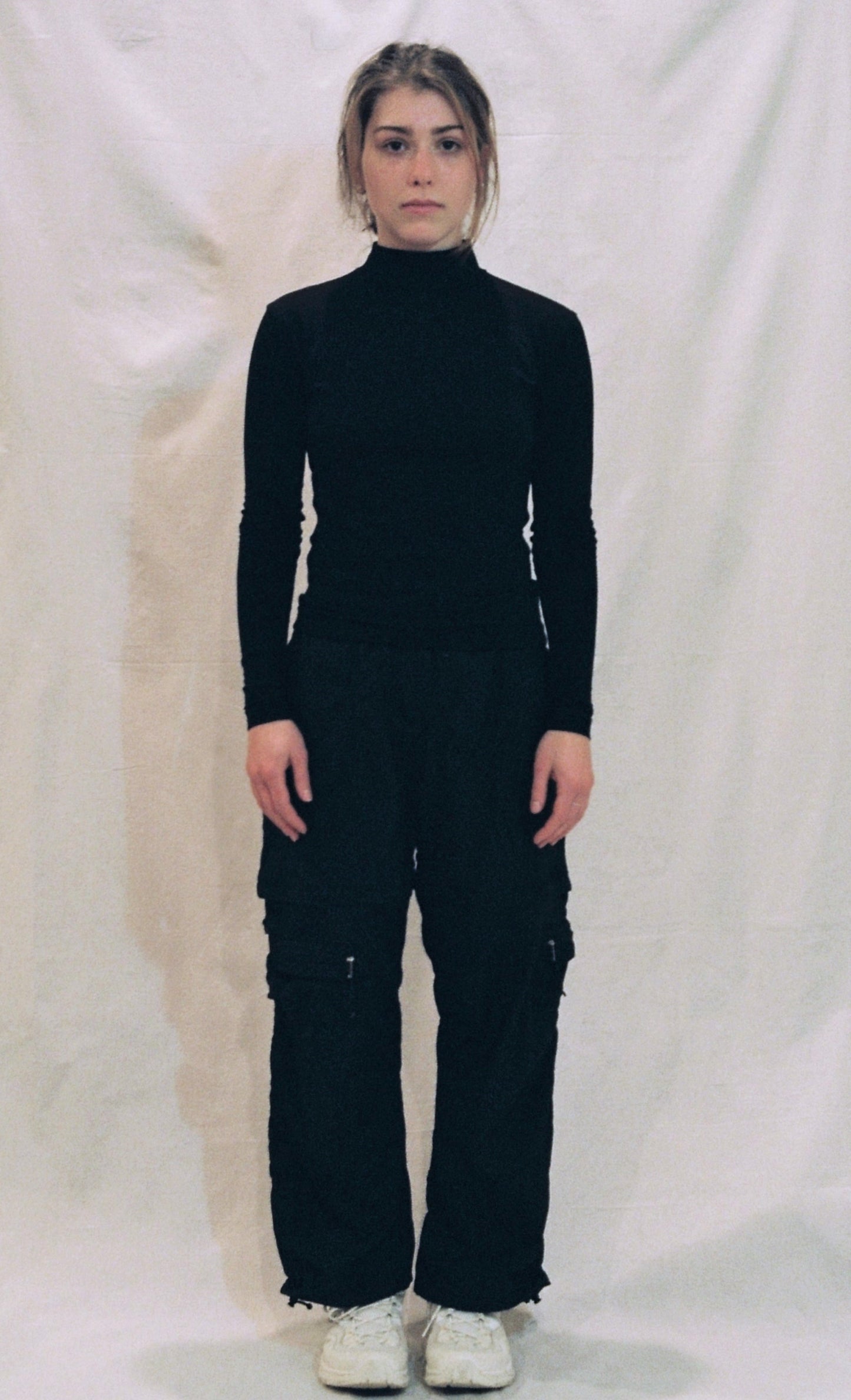 A front photo of a girl standing in front of a white background wearing a black ong sleeve shirt