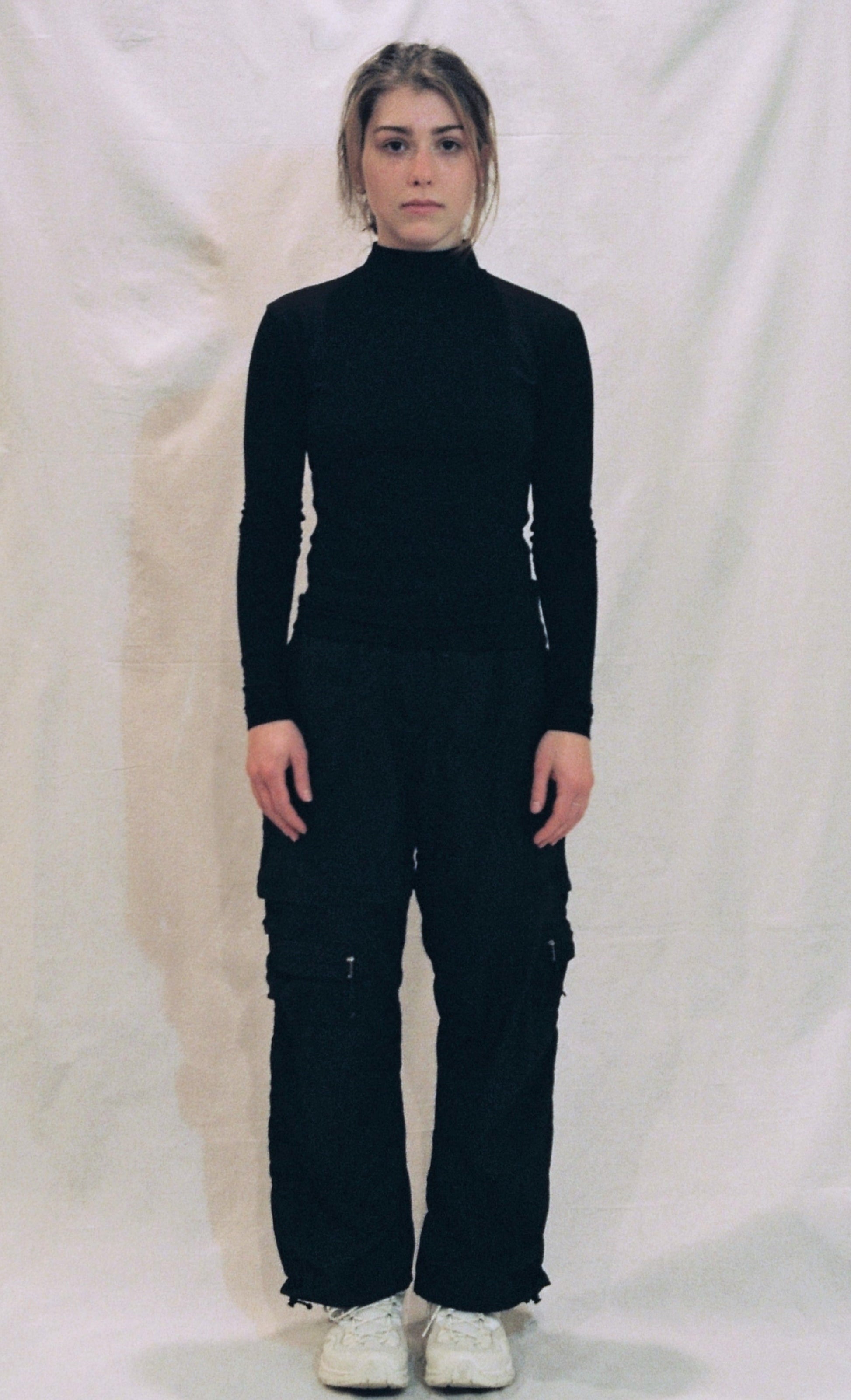 A front photo of a girl standing in front of a white background wearing a black ong sleeve shirt