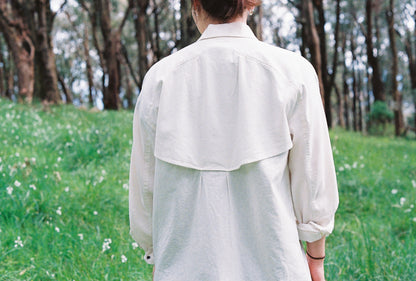 An image of a girl wearing a white shirt with a vent in the back and sleeves rolled up