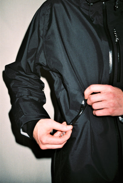 man standing in shell jacket opening front hand pocket