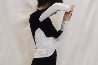 A close up image of a long sleeve shirt viewed from the side with her arm up to show black and white panelling detail