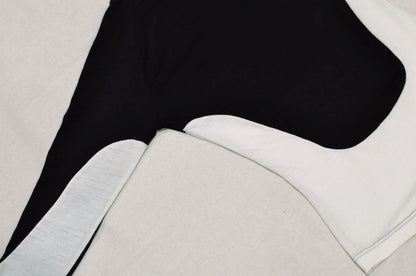 A detailed image of a long sleeve shirt on the side with curved black and white panelling details