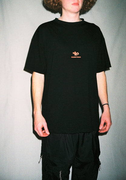 A man standing in front of a white background wearing a black tee shirt with a red logo